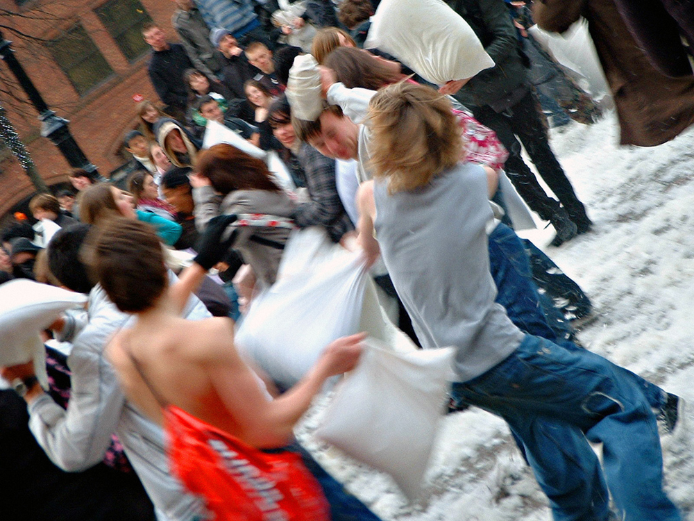 Pessoas brigando de travesseiros ao ar livre são mostradas aqui.