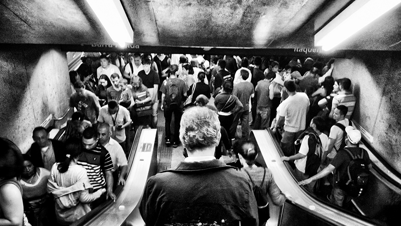 Picha ya kituo cha Subway inaishi kamili ya watu kwenda juu na chini escalators