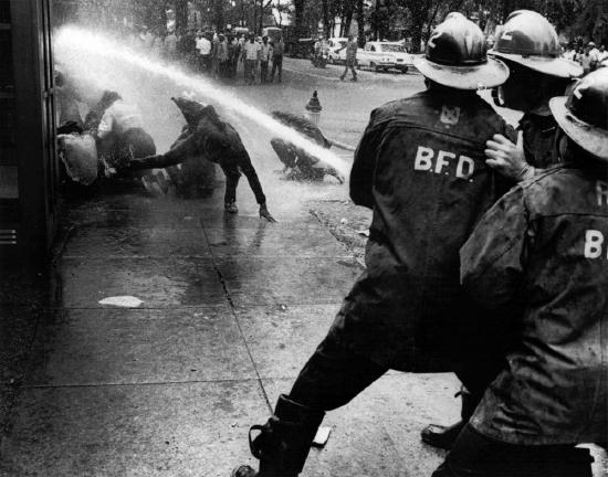 Police soaking demonstrators with a hose. The force of the water appears to have been enough to knock demonstrators off of their feet.