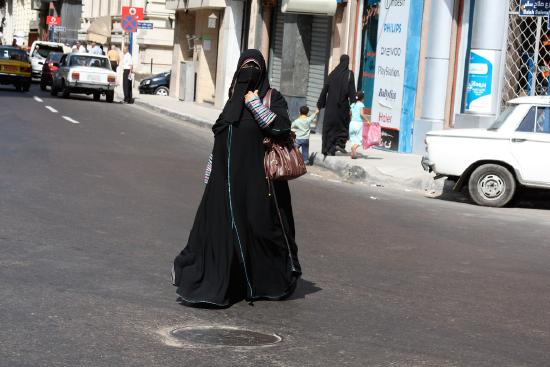 Woman wearing a Burka walking across a street in Cairo Egypt