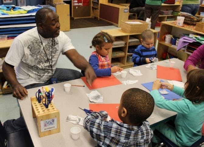 Male teacher at table with 4 children