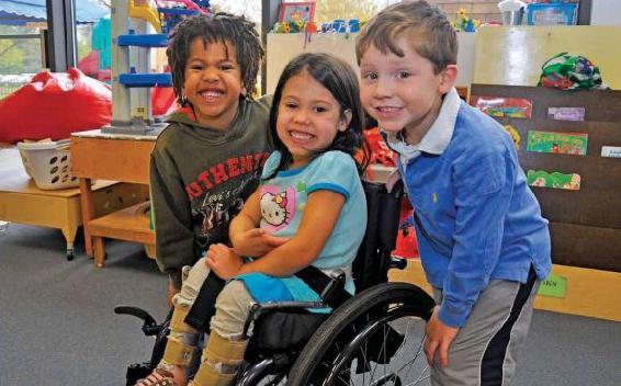 tres niños sonrientes (incluyendo uno en silla de ruedas)