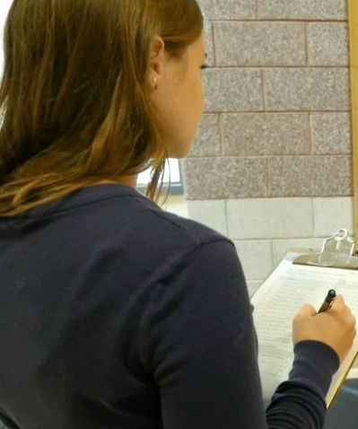mujer escribiendo en papel en portapapeles