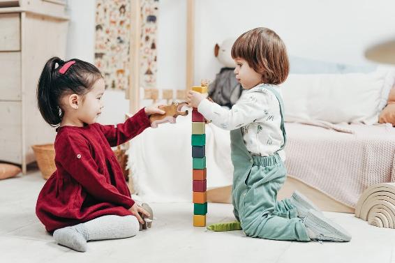 Dos niños jugando con bloques de lego en piso