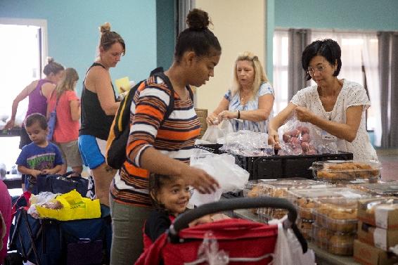 familias con niños pequeños recibiendo comida en el banco de alimentos
