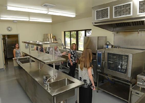 Padres de familia hacen un recorrido por la nueva cocina instalada en la Edad Escolar Anexo 15 de agosto. El anexo fue reabierto luego de un proyecto de renovación de siete meses. (Foto de la Fuerza Aérea de los Estados Unidos por Kenji Tholoweit)