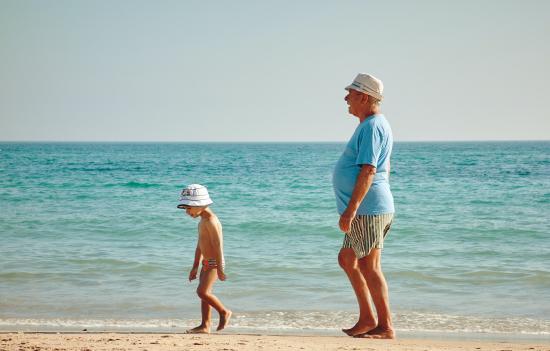 Young boy and old man walking on the beach.