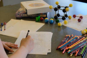Estudiante tomando notas con lápices y modelos de química