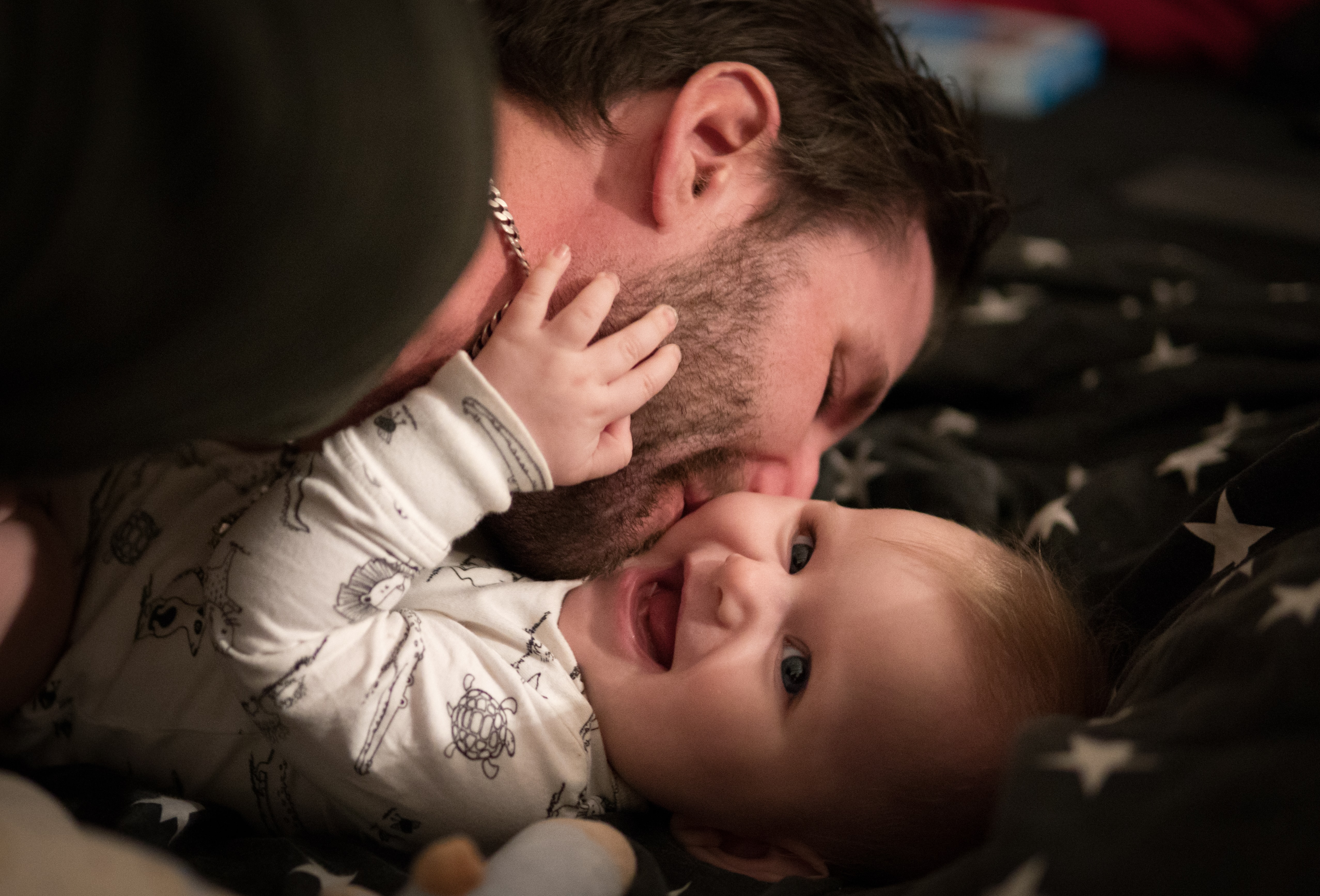 A father kisses a laughing baby.