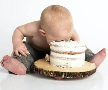 An infant face-planting into a cake.