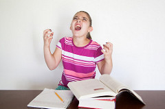 Girl screaming with anger and frustration as she works on some homework.