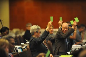 Committee members voting with green cards.