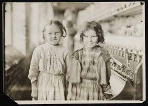 Two young girls working in a textile factory in 1909.