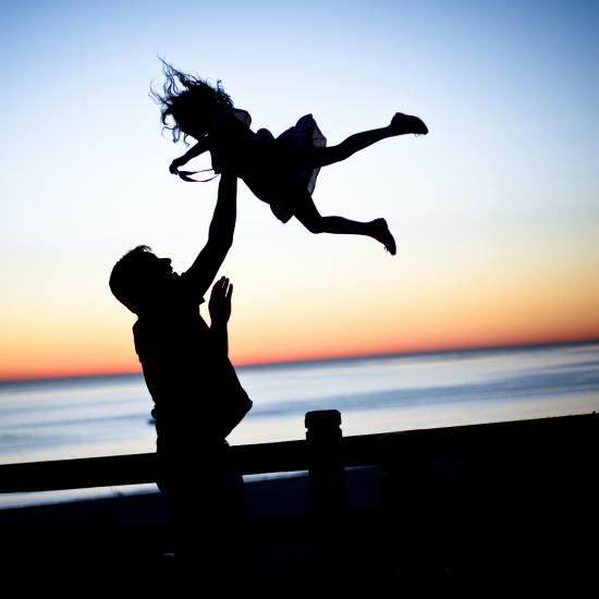 A father tosses a child in the air.