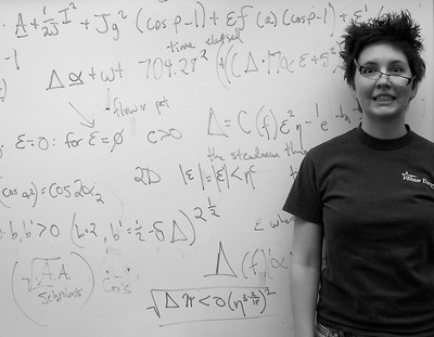 A woman with crooked glasses stands in front of a mess of math equations..jpg