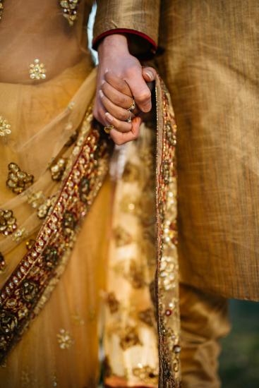 A couple dressing in wedding attire holding hands.