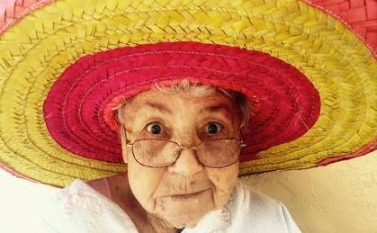 An elderly woman in a large hat - she looks happy and light-hearted.