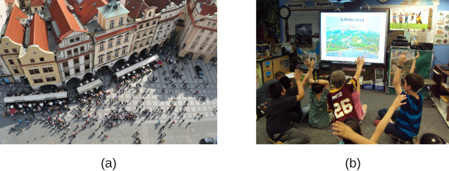 (a) Uma fotografia mostra uma vista aérea de multidões em uma rua. (b) Uma fotografia mostra um pequeno grupo de crianças.