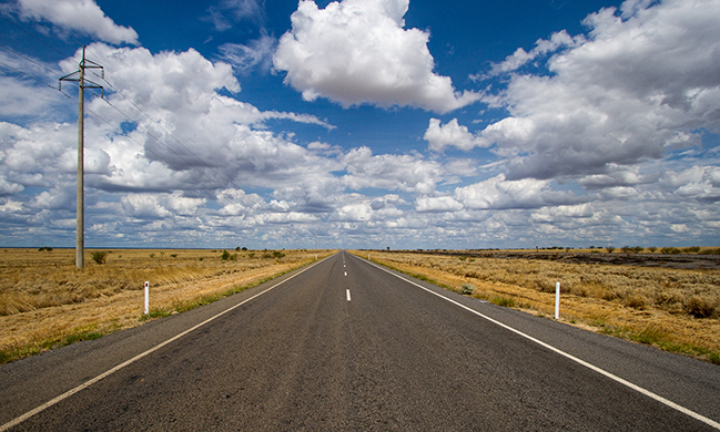 Uma fotografia mostra uma estrada vazia que continua em direção ao horizonte.