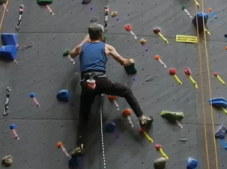 一张照片显示一个戴着安全带的人登上攀岩墙。