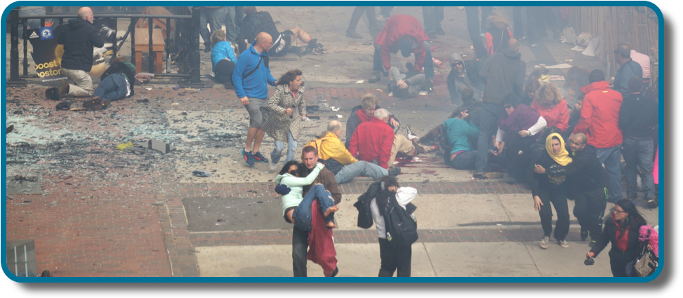 تظهر صورة حشدًا في موقع تفجير ماراثون بوسطن فور وقوعه. الحطام مبعثر على الأرض، ويبدو أن العديد من الأشخاص مصابون، والعديد من الأشخاص يساعدون الآخرين.