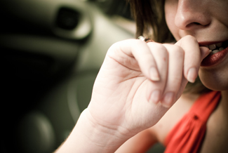Uma fotografia mostra uma mulher roendo as unhas.