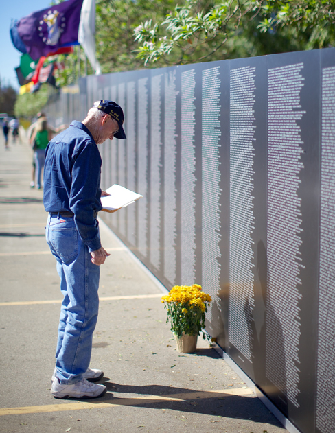 Une photographie montre une personne regardant le mur commémoratif itinérant du Vietnam.