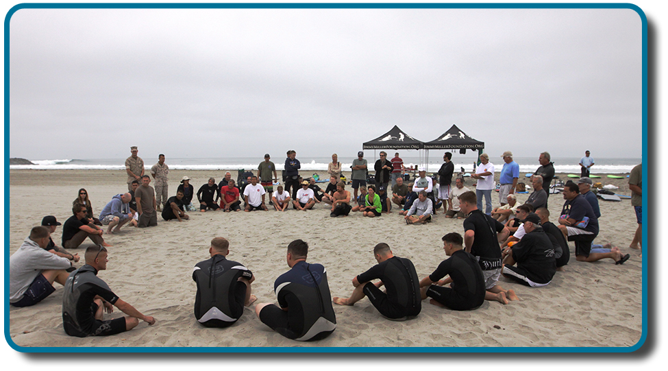 Cette photo représente un grand groupe de personnes assises en cercle sur la plage.