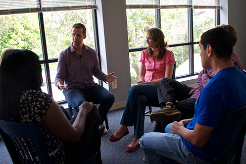 Un groupe de personnes disposées en cercle ayant une conversation est représenté.