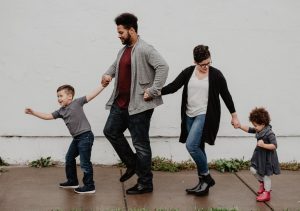 Photo of a father, mother, son and daughter walking together on a sidewalk
