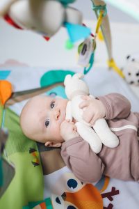 photo of a baby holding and sucking on a toy