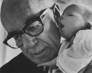 Una foto en blanco y negro del Dr. Spock, un anciano, sosteniendo a un bebé.