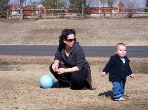 A person sitting near a small child who is standing up and looking around.