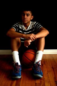 a photo of a boy sitting on the ground with a basketball
