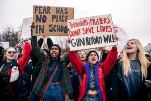 Una foto de adultos jóvenes sosteniendo carteles protestando por leyes de armas en la Casa Blanca