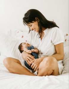 photo of a woman smiling while holding her baby