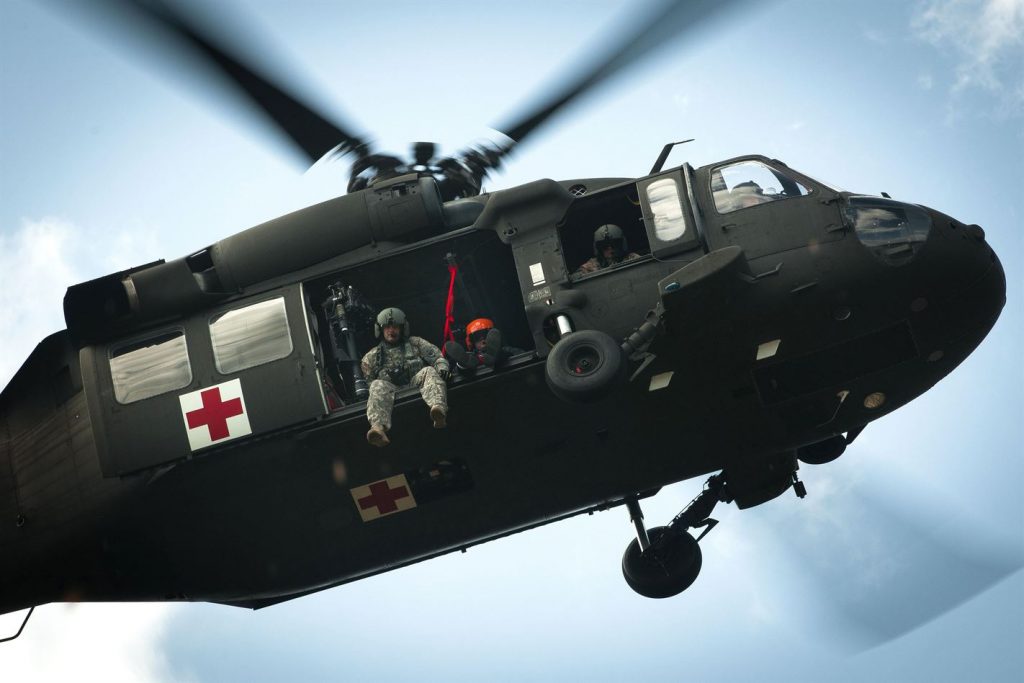 un helicóptero del ejército se cierne sobre la cabeza, con soldados mirando a la cámara