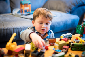 a young boy plays with train toys at a table