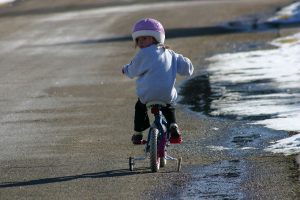 a young girl riding a bike with her head turned looking behind her