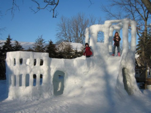 photo of a large snow fort with two children on it
