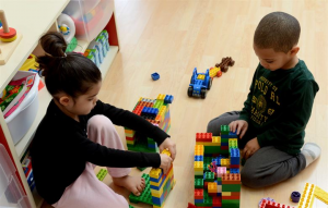 two children play with Legos together on the floor
