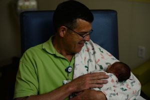 A man sitting holding a newborn infant