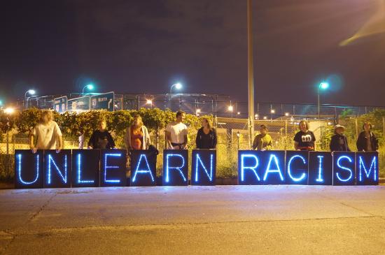 Protesters holding a sign reading unlearn racism