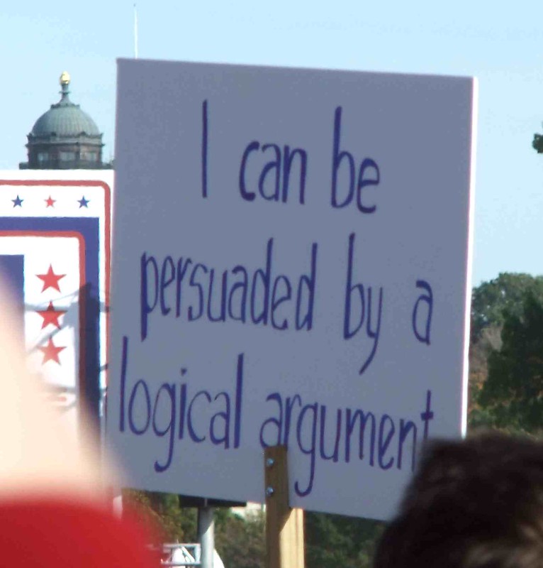 protest sign that reads "I can be persuaded by a logical argument"