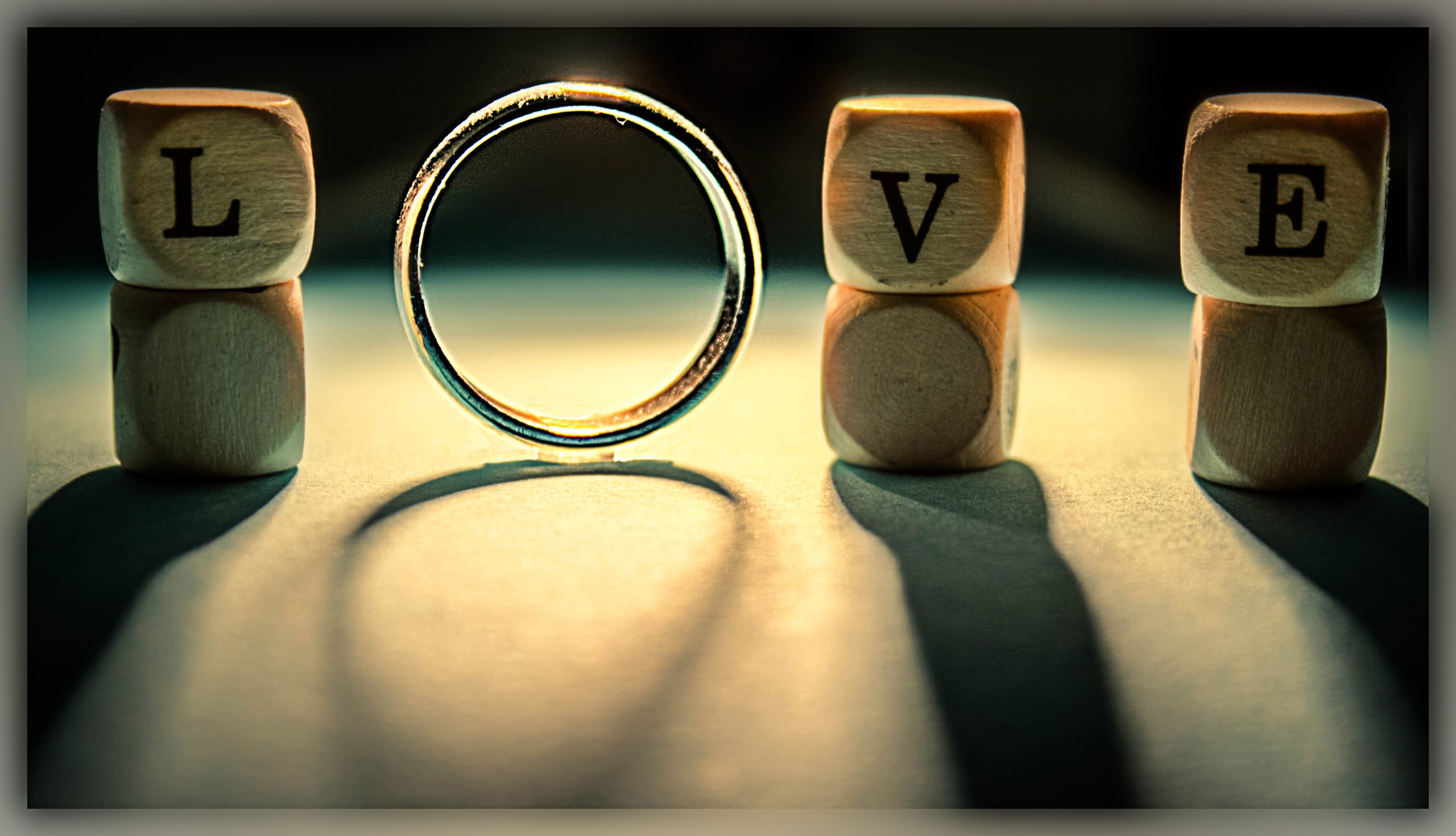 The word love. The letters L, V and E are in wooden blocks. The letter O is represented by a wedding ring.