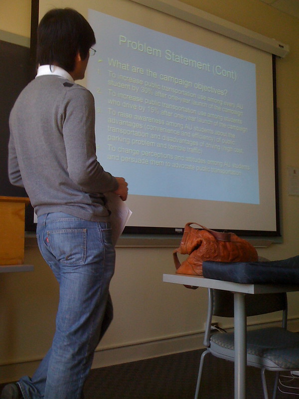 man giving a presentation with a PowerPoint on the projector screen behind him