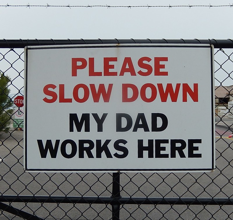a sign on a fence that reads "Please slow down. My dad work here".