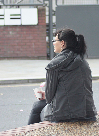 Woman sitting alone outside, coffee in hand
