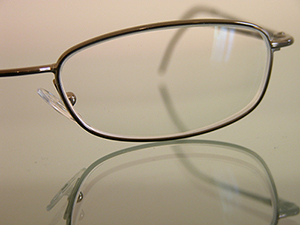 Closeup of half of a par of prescriotion glasses on a reflective surface