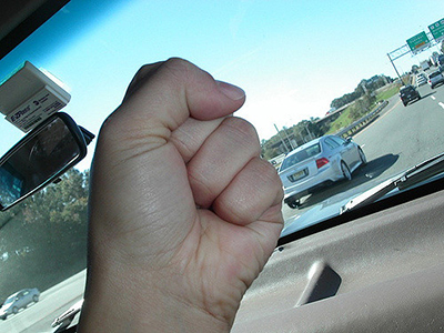 Fist inside a car, raised angrily at traffic